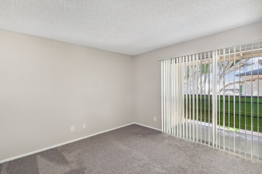 an empty living room with a large window and white blinds